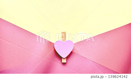 heartfelt romantic pink envelope clipped by purple heart wooden clothespin on vibrant yellow backdrop heartfelt romantic pink envelope clipped by purple heart wooden clothespin on vibrant yellow backdrop 139624142