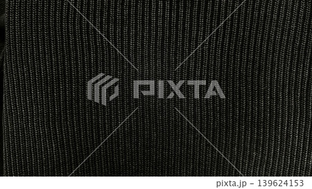 black ribbed knit fabric texture closeup reveals vertical ribs in tactile macro detail with minimalist dark elegance 139624153