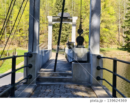 Scenic Outdoor Bridge. Suspension Bridge With Cable Supports And Sunlit Walkway For Leisure Strolling 139624369