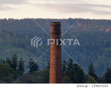 Weathered Masonry Stands Atop Mountain Ridge. Moody Dusk Sky Enhances Solitary Brick Chimney Tower Scene Weathered Masonry Stands Atop Mountain Ridge. Moody Dusk Sky Enhances Solitary Brick Chimney Tower Scene 139624385