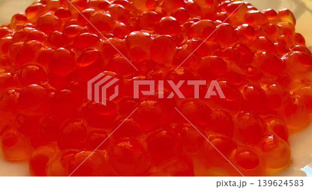 A plate showcasing vibrant red fish caviar, elegantly presented on a pristine white dish A plate showcasing vibrant red fish caviar, elegantly presented on a pristine white dish 139624583