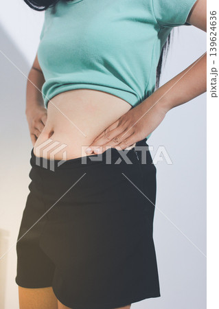 Flabby belly after pregnancy, overweight female body on gray background 139624636