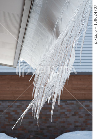 Row of icicles hanging from eaves on a roof 139624707