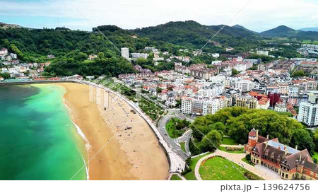 An aerial view shows a picturesque town between lush, green mountains by the coast An aerial view shows a picturesque town between lush, green mountains by the coast 139624756