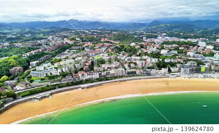 Stunning Aerial View of a Coastal Town Featuring a Beach and Majestic Mountains Nearby 139624780
