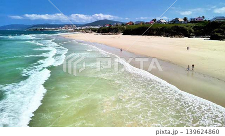 A stunning beach landscape featuring gentle waves against a backdrop of a bright blue sky 139624860