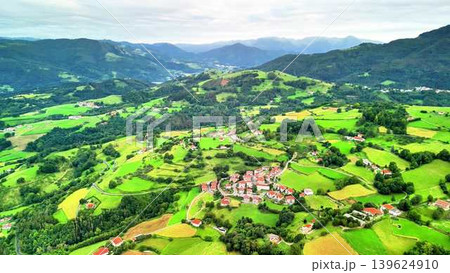 An aerial view highlights a quaint villages beauty, nestled in lush green hills An aerial view highlights a quaint villages beauty, nestled in lush green hills 139624910