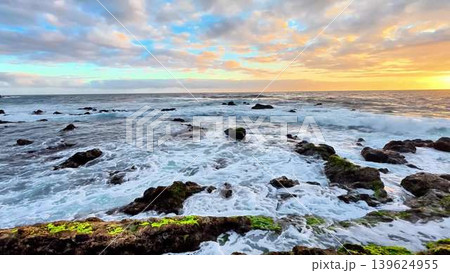 A stunning coastal sunset casts colorful reflections on dynamic waves and rocky shoreline A stunning coastal sunset casts colorful reflections on dynamic waves and rocky shoreline 139624955