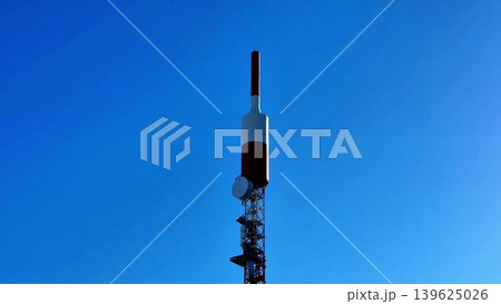 A tall telecommunications tower stands proudly against the backdrop of a clear blue sky A tall telecommunications tower stands proudly against the backdrop of a clear blue sky 139625026