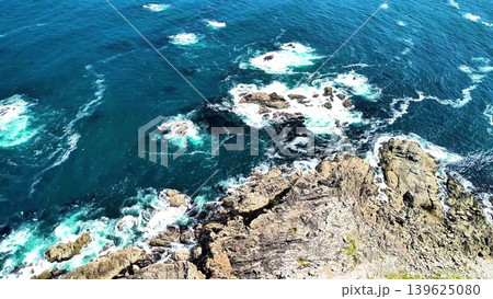 A breathtaking Aerial View of Turquoise Ocean Waves Powerfully Crashing on Rocky Coastline 139625080