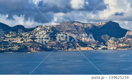 A breathtakingly stunning coastal landscape showcasing majestic mountains under a cloudy sky A breathtakingly stunning coastal landscape showcasing majestic mountains under a cloudy sky 139625239