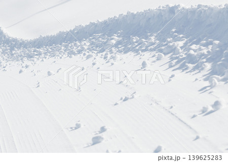 Lumps of snow at curved edge of groomed ski slope 139625283