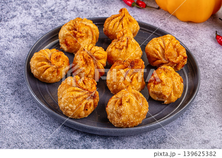 Golden fried dumplings momo in a skillet with fresh vegetables and flatbread Golden fried dumplings momo in a skillet with fresh vegetables and flatbread 139625382