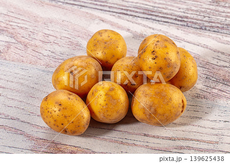 Fresh raw organic yellow potatoes on light rustic wooden background Fresh raw organic yellow potatoes on light rustic wooden background 139625438