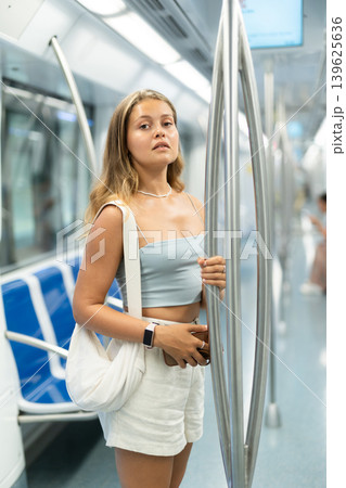Young woman is standing in subway car with phone, getting to work school. Young woman is standing in subway car with phone, getting to work school. 139625636