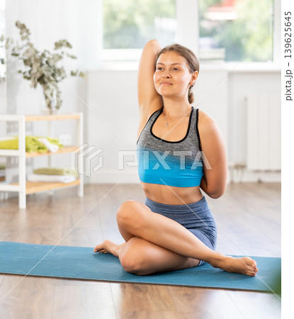 Sportive girl practicing cow face pose of yoga in light room Sportive girl practicing cow face pose of yoga in light room 139625645