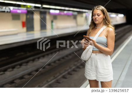 Young woman with phone stands at metro station Young woman with phone stands at metro station 139625657
