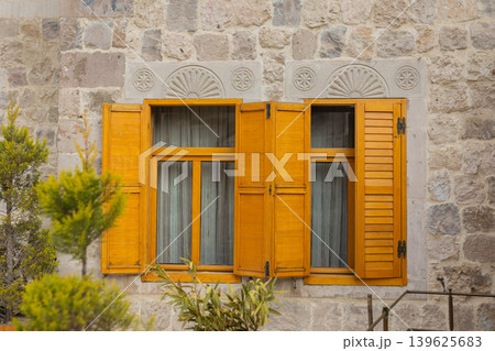 Traditional wooden windows on stone house facade close up Traditional wooden windows on stone house facade close up 139625683