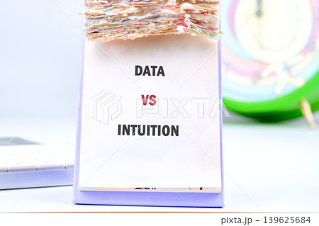 A white desk calendar with many pages displays DATA VS INTUITION in bold letters 139625684