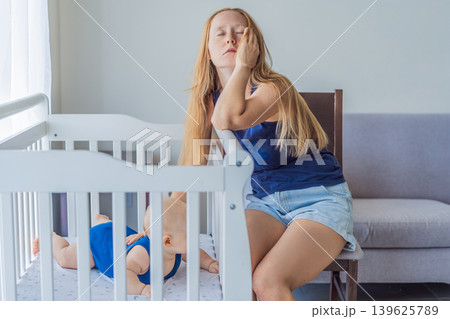 Very tired mother sitting by baby crib at home feeling exhausted. Sleep deprived mom caring for newborn at night. Parenting fatigue, motherhood stress, childcare and real family life concept Very tired mother sitting by baby crib at home feeling exhausted. Sleep deprived mom caring for newborn at night. Parenting fatigue, motherhood stress, childcare and real family life concept 139625789