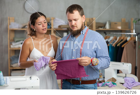 Male tailor discussing textile with girl Male tailor discussing textile with girl 139626726