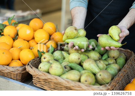 Male seller's hands placing pears on store counter Male seller's hands placing pears on store counter 139626758