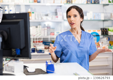 Female pharmacist standing behind counter in drugstore 139626793