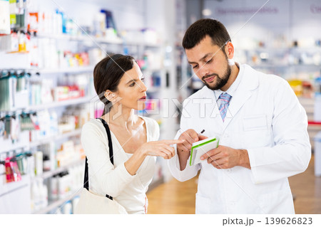 Male pharmacist advising woman customer in drugstore Male pharmacist advising woman customer in drugstore 139626823