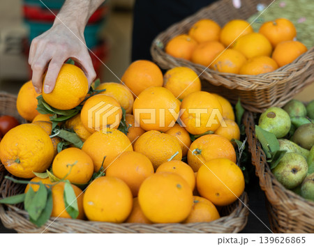 Close-up of male seller's hands placing oranges on shop counter 139626865