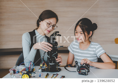 Female Teacher Explaining Robotic Arm Structure to Student in STEM Engineering Workshop Female Teacher Explaining Robotic Arm Structure to Student in STEM Engineering Workshop 139628052