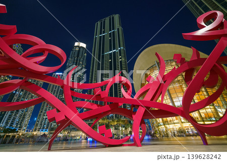 Dubai, United Arab Emirates - Jan 19 2024, panoramic view of sculpture in form of Arabic script called Declaration, in background facade of Dubai Opera and skyscrapers, at nighttime, Dubai, UAE 139628242