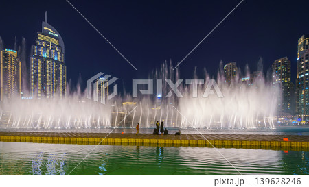 Dubai, United Arab Emirates - Jan 19 2024, Panoramic view of the Dancing fountains in the pool next to the Burj Khalifa, at night with the lights on, people walking around, Dubai, UAE Dubai, United Arab Emirates - Jan 19 2024, Panoramic view of the Dancing fountains in the pool next to the Burj Khalifa, at night with the lights on, people walking around, Dubai, UAE 139628246