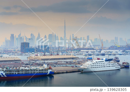 Dubai, United Arab Emirates - Jan 19 2024, Panoramic sea view of Dubai skyscrapers and port facilities in the foreground, at early morning, Dubai, United Arab Emirates  139628305