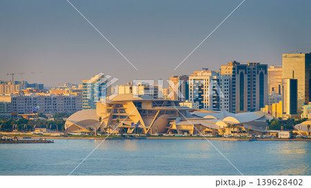 Doha, Qatar - Jan 14 2024, Panoramic sea view of the Qatar National Museum, in the shape of a desert rose, with downtown buildings and skyscrapers in the background, at daytime, Doha, Qatar 139628402