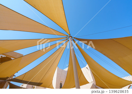 Doha, Qatar- Jan 14 2024, 4k, Bottom-up view of several triangular fabric awnings connected to a pillar in the center, covering the street from sun, Katara cultural village, at daytime, Doha, Qatar Doha, Qatar- Jan 14 2024, 4k, Bottom-up view of several triangular fabric awnings connected to a pillar in the center, covering the street from sun, Katara cultural village, at daytime, Doha, Qatar 139628635