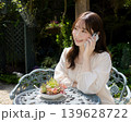 庭で在宅ワークのためにスマホを使う女性 庭で在宅ワークのためにスマホを使う女性 139628722