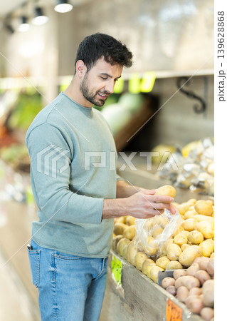 Male shopper selects potatoes from shelves of grocery supermarket Male shopper selects potatoes from shelves of grocery supermarket 139628868