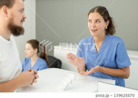 man is standing near the reception in the dentistry and asks about an appointment with a dentist 139628870