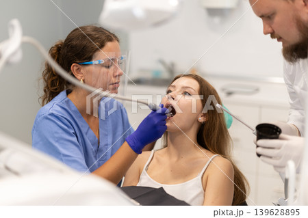 Female dentist treats a client teeth together with an assistant in the office 139628895