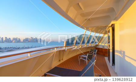 Doha, Qatar - Jan 14 2024, Panoramic view of the terrace with deck chairs of the luxury cabin on the MSC Virtuosa cruise ship, in the background the skyscrapers of Doha, at sunset, Doha, Qatar 139628912