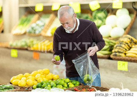 Senior man stands in the middle of a supermarket near a citrus fruit counter 139628962