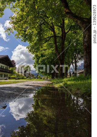 Puddle Reflection of Green Trees and Clouds After Rain in a Bavarian Village Puddle Reflection of Green Trees and Clouds After Rain in a Bavarian Village 139628973