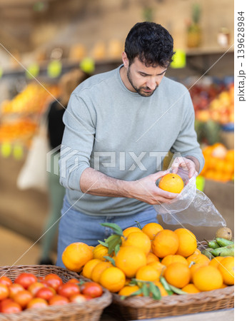 Adult man chooses oranges in store Adult man chooses oranges in store 139628984