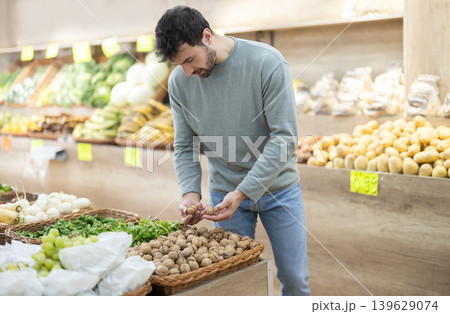 Man holding bag to weigh nuts before buying in farm store Man holding bag to weigh nuts before buying in farm store 139629074