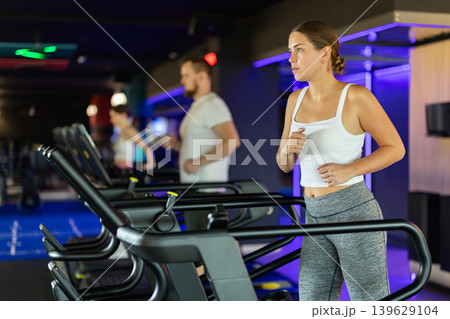 Girl in gym runs with help of treadmill Girl in gym runs with help of treadmill 139629104