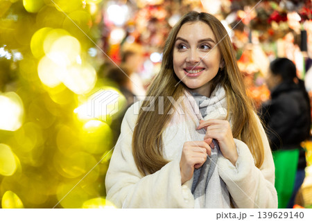 Girl stands in middle of shopping area decorated for New Year holidays Girl stands in middle of shopping area decorated for New Year holidays 139629140