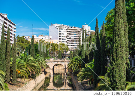 Palma de Mallorca cityscape with canal, trees, stone bridge and sunlit buildings in Spain Palma de Mallorca cityscape with canal, trees, stone bridge and sunlit buildings in Spain 139630016
