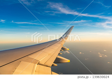Airplane wing in flight over the ocean with blue sky and clouds, travel and transportation Airplane wing in flight over the ocean with blue sky and clouds, travel and transportation 139630024