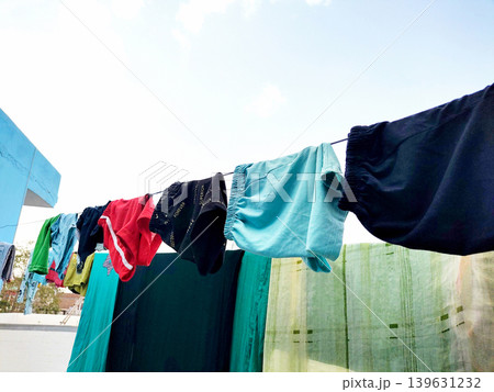 Clothes Drying on a Rope Against Blue Wall Outdoors 139631232