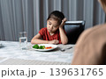 Mother is telling her cute kid eat useful vegetables but the child refuses to eat. 139631765
